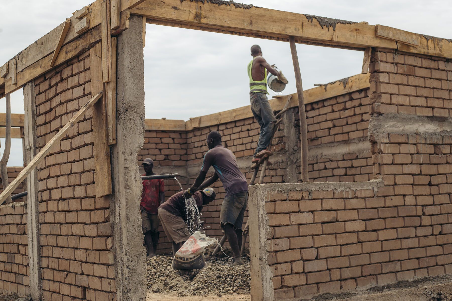 Young men raising the walls of a brick building