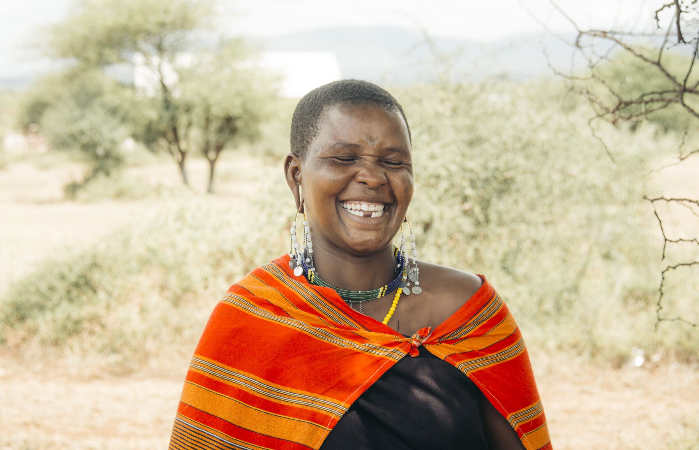 Young woman laughing in an orange shuka